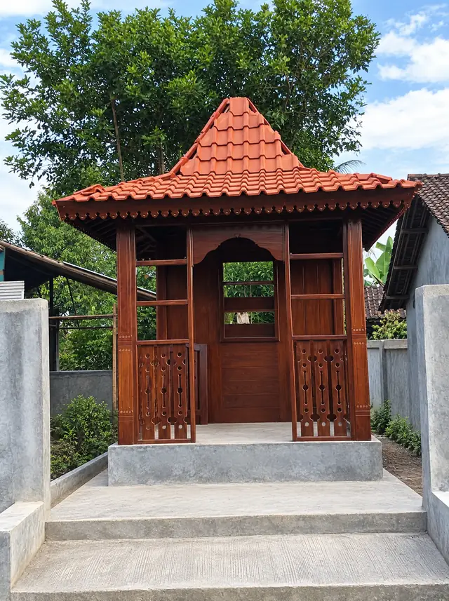 Gazebo kayu gelap beratap genteng dengan pagar dan pintu berukir