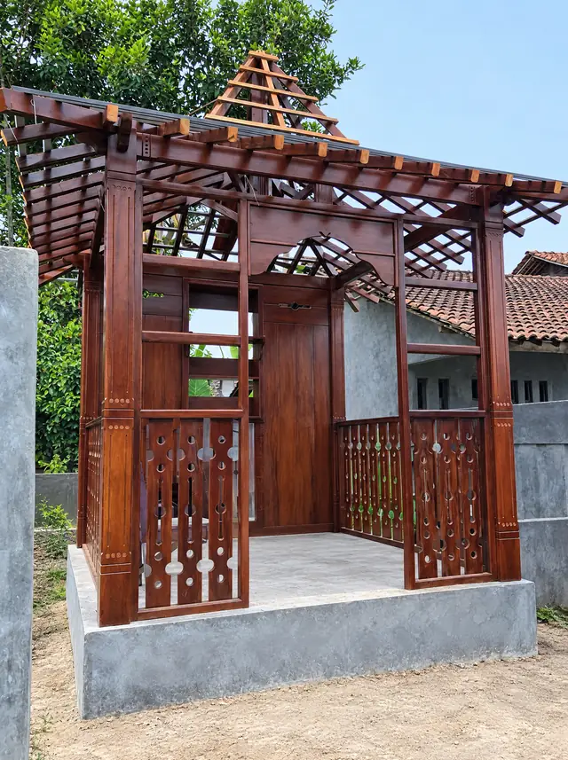 Gazebo kayu gelap berukir saat rangka atapnya belum ditutup genteng