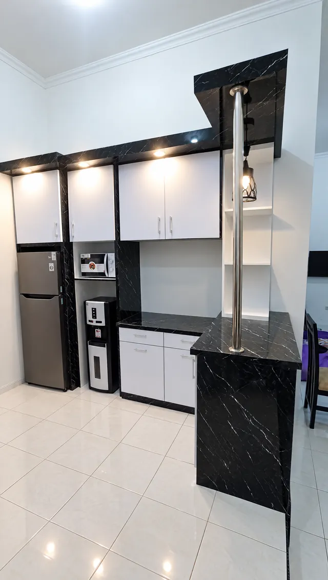 Meja bar motif marmer hitam dengan tiang stainless di ujung kitchen set